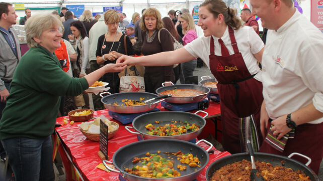 Image shows people buying freshly cooked food at a festival