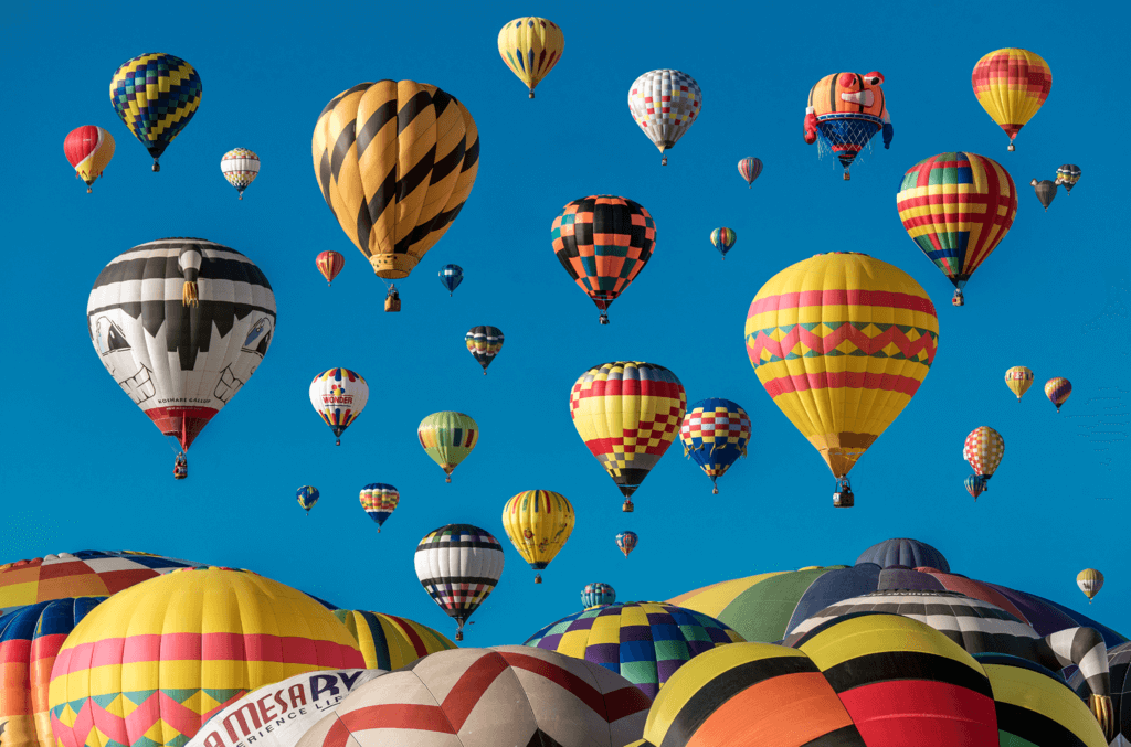 Image shows scores of hot air balloons setting off at a festival